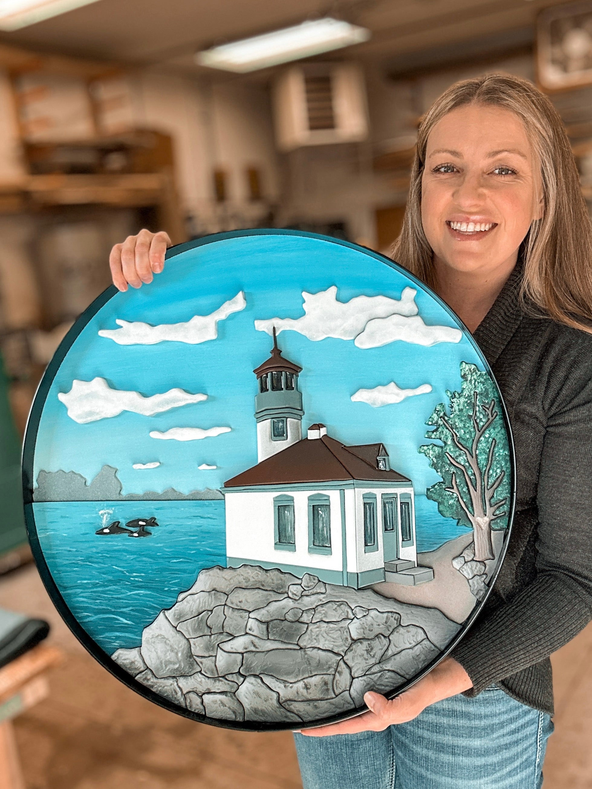 Custom scroll art of a landscape and lighthouse framed in a round black steel frame